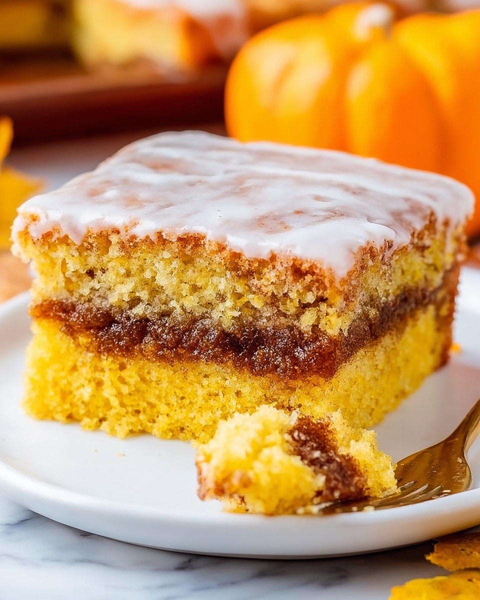 A square piece of orange-yellow cake with a visible middle layer of dark, thick filling sits on a white plate, with a woman's hand holding a fork breaking off a corner piece showing its soft texture. The cake has a shiny, light glaze on top, giving it a slightly wet look. In the background, there is an orange pumpkin and some autumn leaves. The plate is placed on a white marbled surface, with a warm, cozy autumn vibe. Photo taken with an iphone --ar 4:5 --v 7