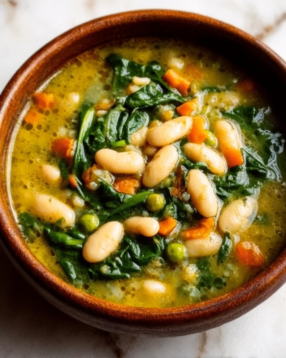 This image shows a bowl of thick soup filled with white beans and leafy green spinach, along with small orange carrot pieces, all mixed in light yellow broth. The soup has a soft, smooth texture with visible chunks of beans and vegetables. The bowl is white and round, set on a white marbled surface. The soup looks warm and hearty, with the colors of the ingredients standing out clearly. Photo taken with an iphone --ar 4:5 --v 7